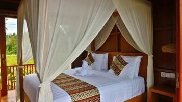 A four-poster canopy bed with a patterned bedspread, a wooden headboard, and a view of the outdoors.