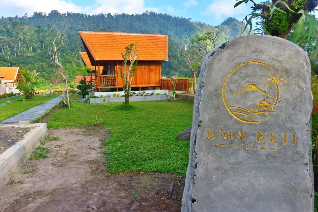 A stone sign with 'UMA BEIJ VILLA' and a palm tree symbol, indicating a villa setting.