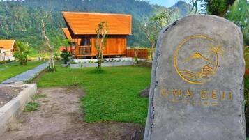A stone sign with 'UMA BEIJ VILLA' and a palm tree symbol, indicating a villa setting.