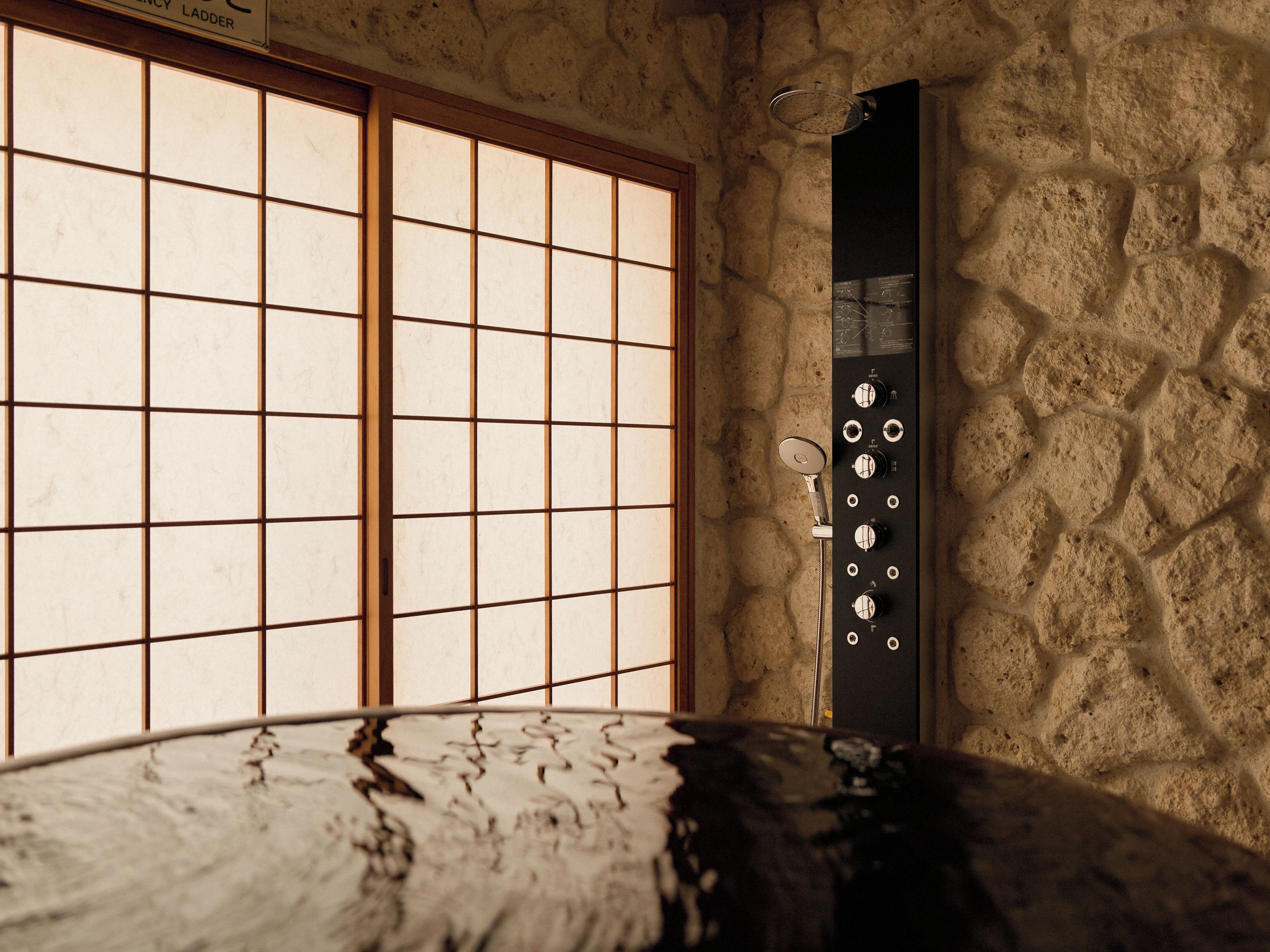 Un baño con pared de piedra, una bañera y una ventana con diseño de cuadrícula.