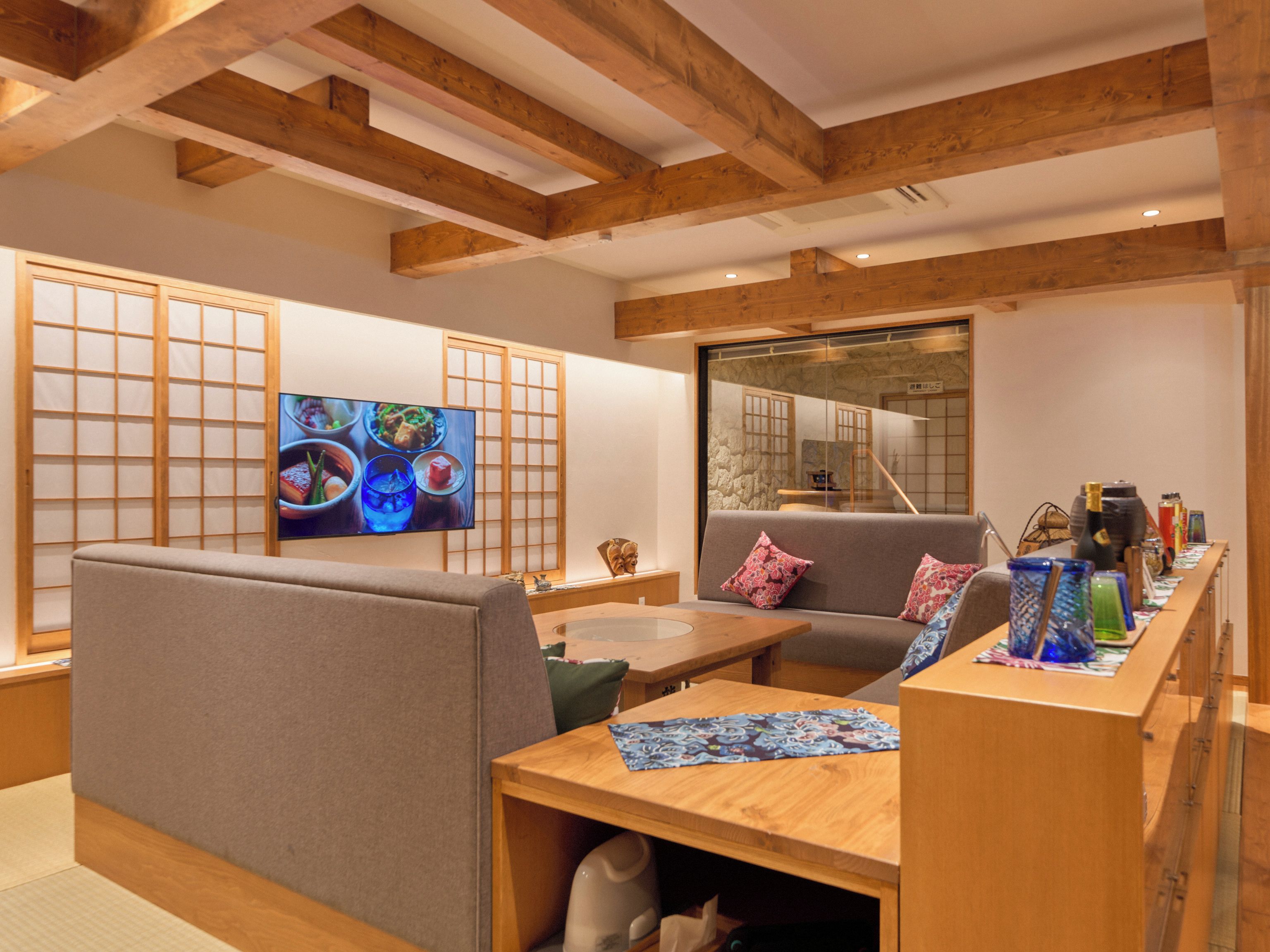 Una habitación tradicional japonesa con suelo de tatami, una mesa baja y un sofá con cojines.