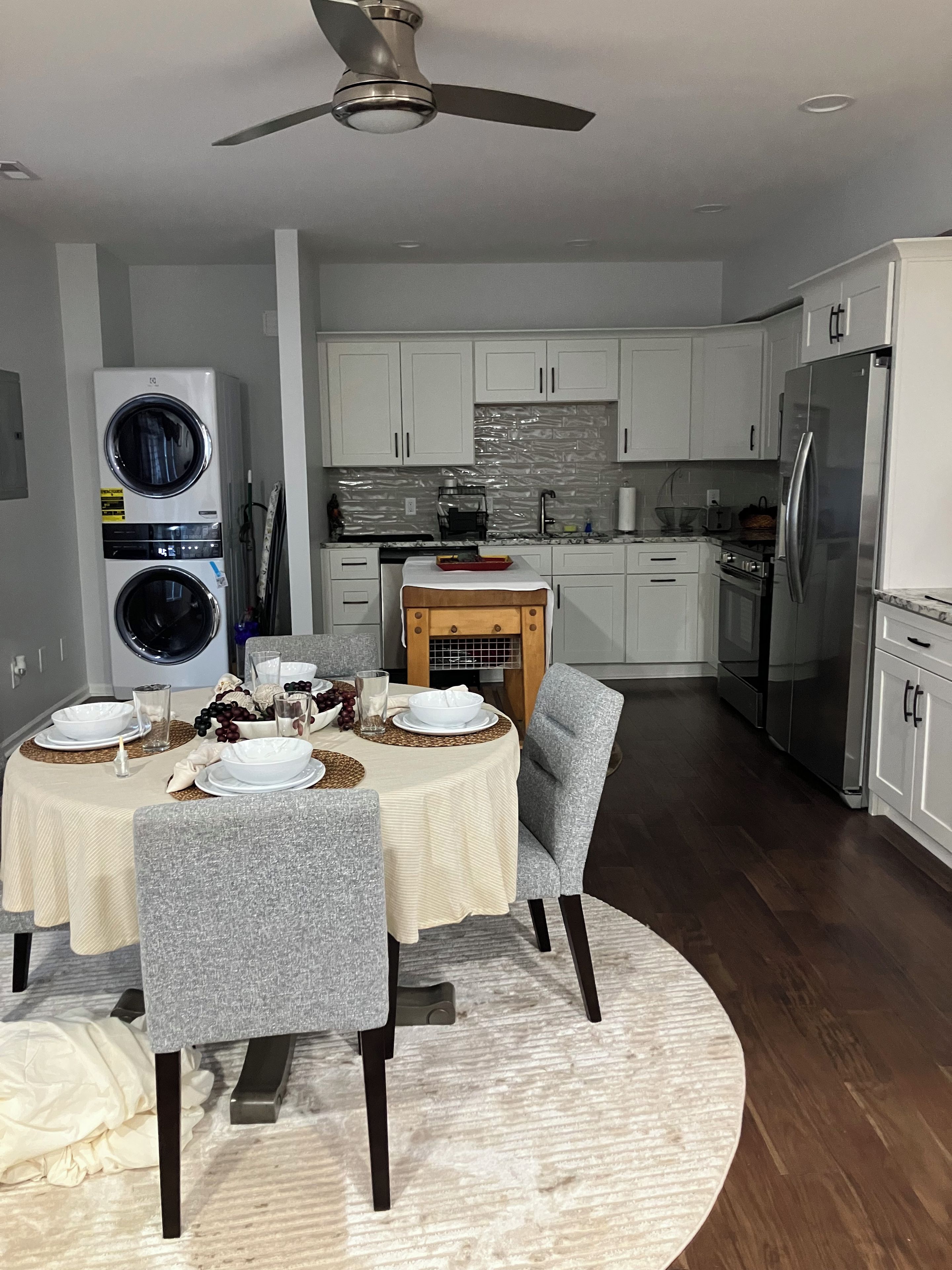 A modern kitchen with a dining area, including a ceiling fan, built-in appliances, and a round dining table with chairs.