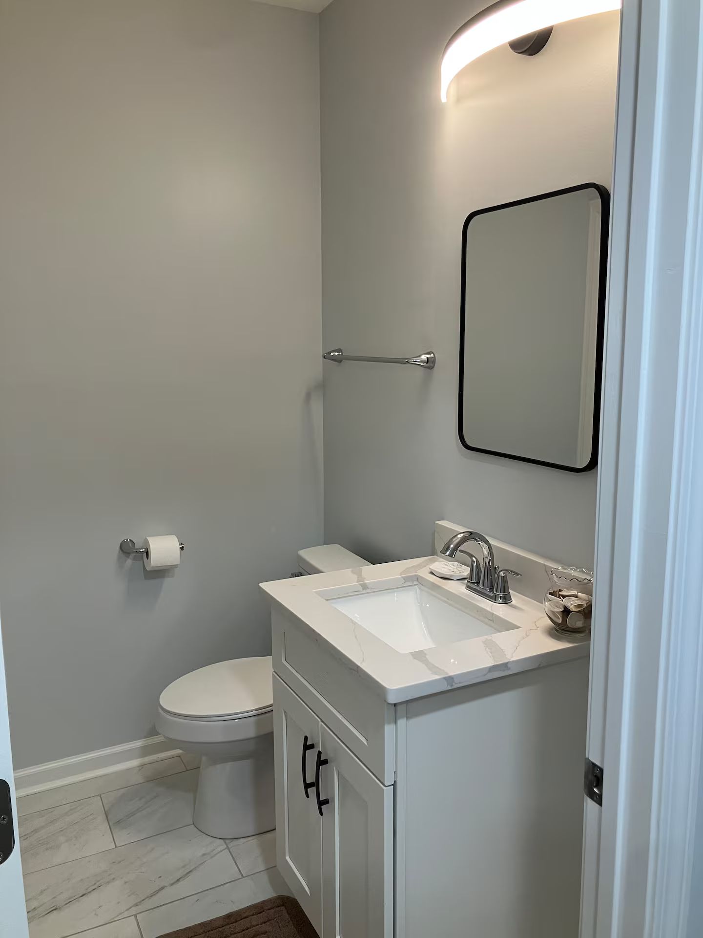 A bathroom with a toilet, sink, and mirror.