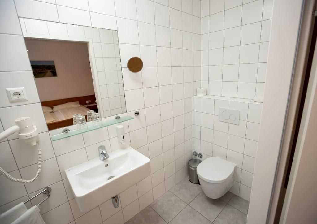 A bathroom with a white sink, mirror, and toilet.