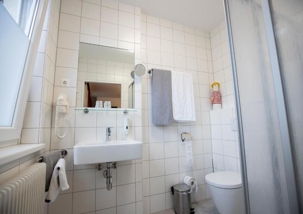 Un baño con lavamanos, espejo y retrete blancos.