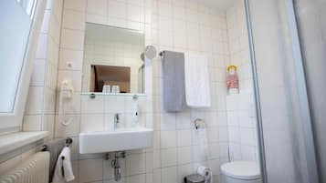 Un baño con lavamanos, espejo y retrete blancos.
