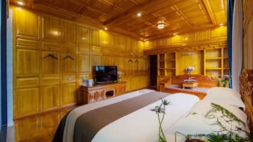 Hotelkamer met houten lambrisering, een flatscreen televisie, een bed met een wit-bruine sprei, een houten nachtkastje en een tafeltje met een bloevas.