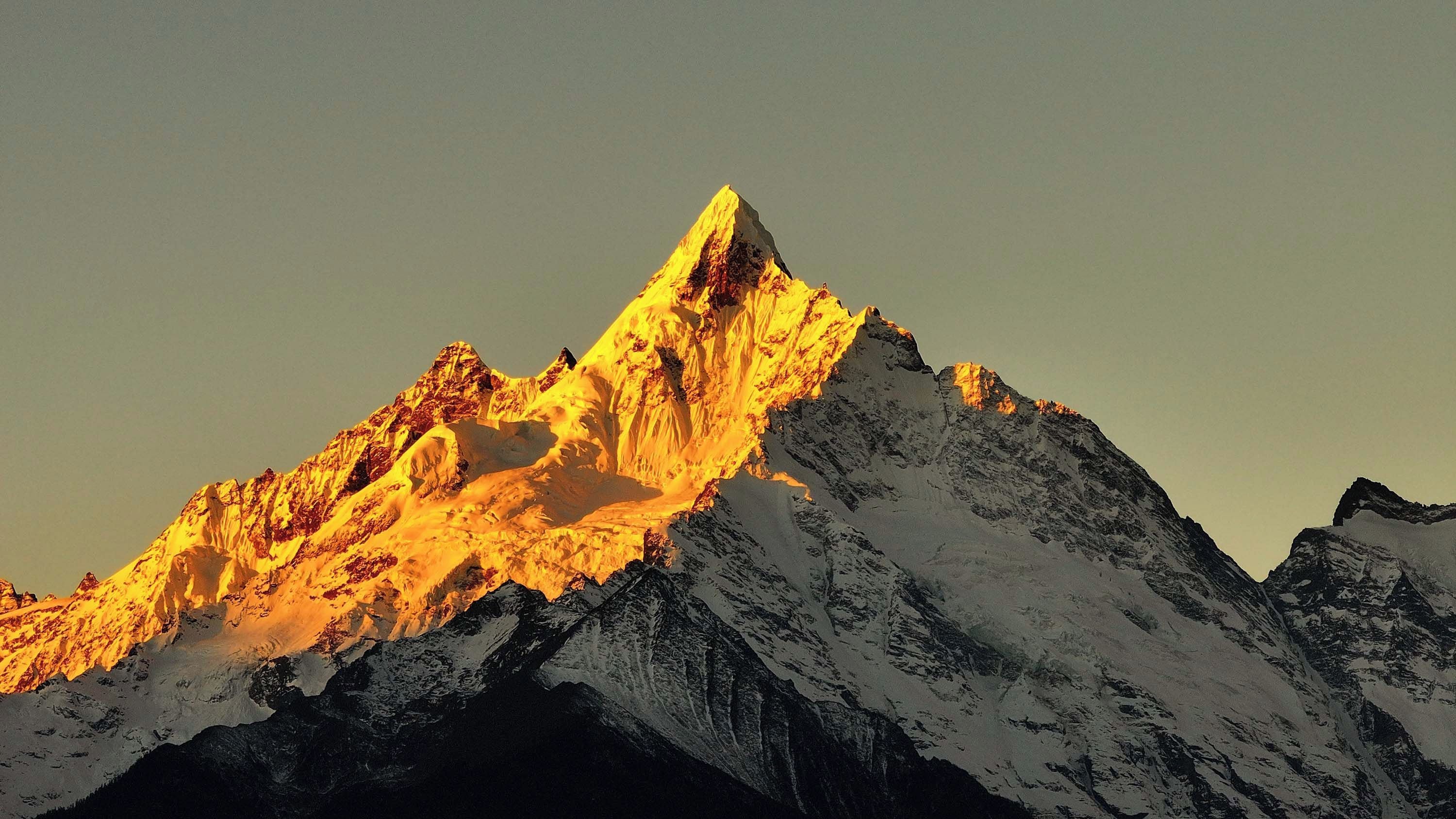 A snow-covered mountain peak with sharp ridges and a clear sky.