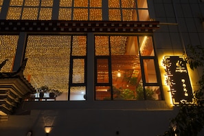 Fachada de edificio con múltiples ventanas, algunas decoradas con luces de cadena.