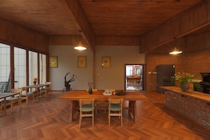 A spacious kitchen with a herringbone floor pattern, wooden furniture, and a brick wall.