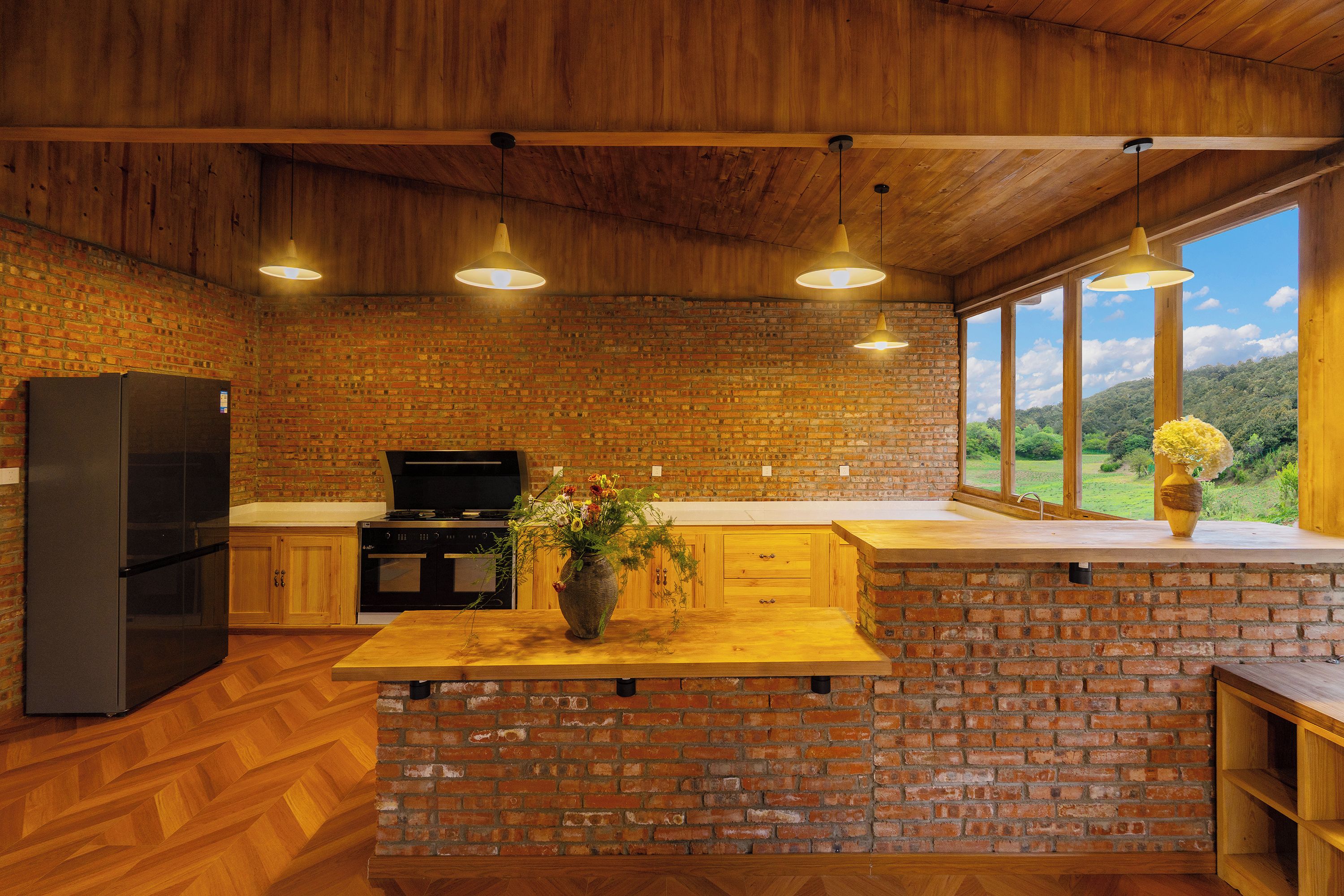 Una cocina con pared de ladrillo, techo de madera y un ventanal con vistas al exterior.