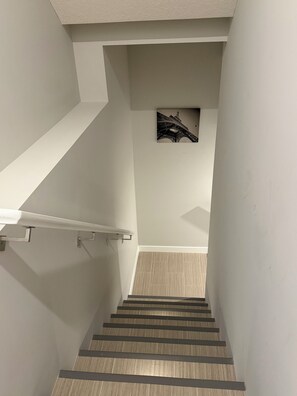 Eine Treppe mit Handlauf, ein an der Wand hängendes Bild des Eiffelturms und ein heller Boden.