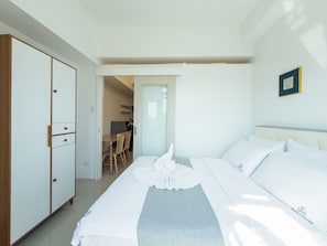 A hotel room with a bed, a wardrobe, and a dining area. - GemstoneBR in Harbour Park Residences (Mandaluyong City)