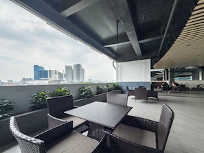 Un espacio al aire libre con mobiliario de mimbre y vistas del horizonte de la ciudad.
