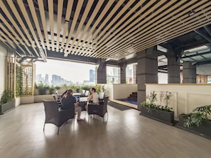 An indoor seating area with a city view, featuring a modern ceiling design and potted plants.