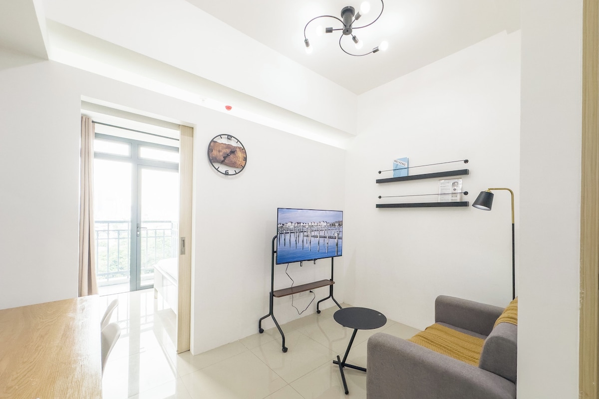 Una sala de estar moderna con un televisor de pantalla plana, una lámpara en el techo, un sofá y una mesa de comedor.