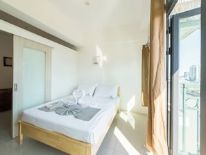 Habitación de hotel con cama, vista a la ciudad y puerta corredera.