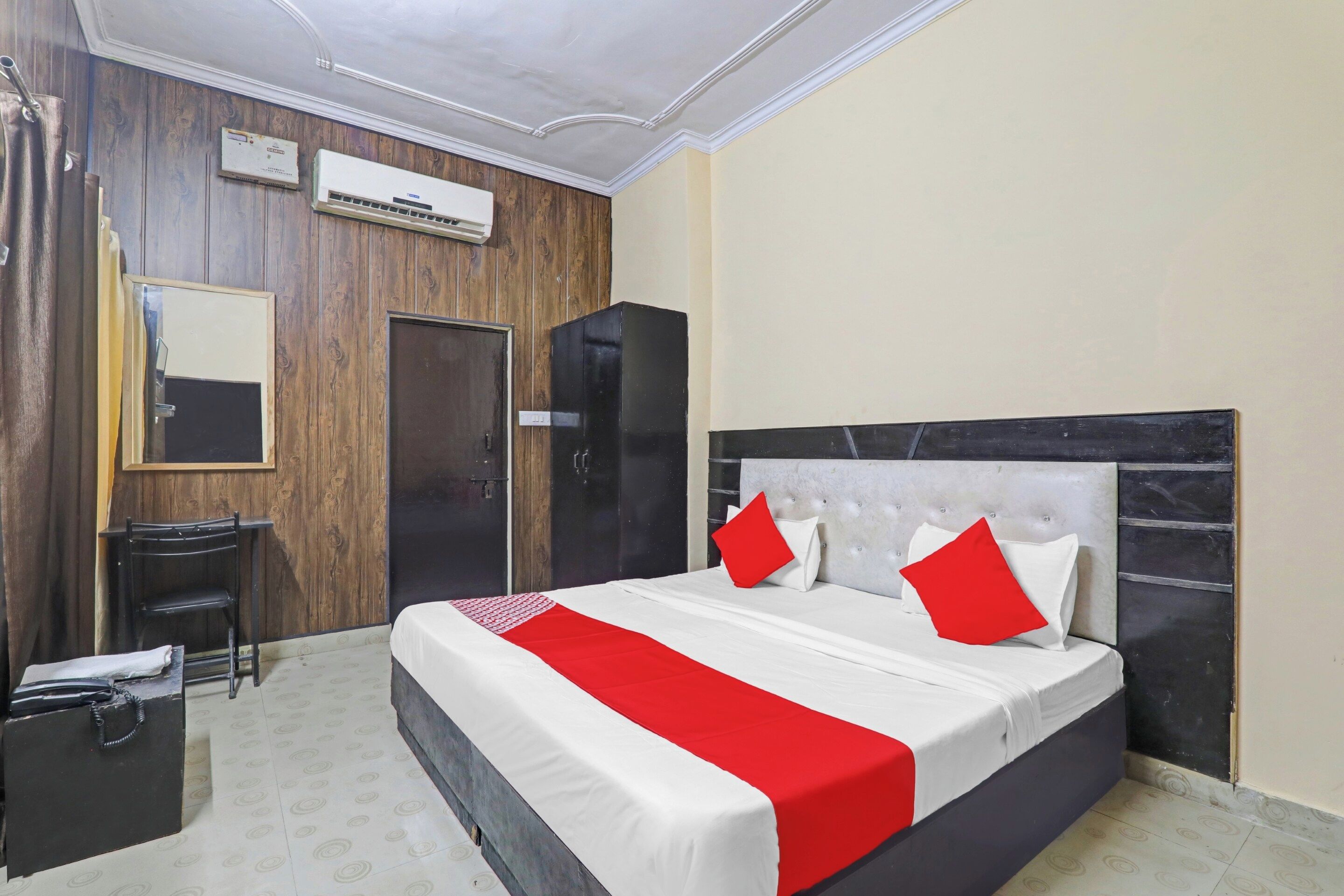 Una habitación de hotel con cama, armario, espejo y una pequeña mesa.
