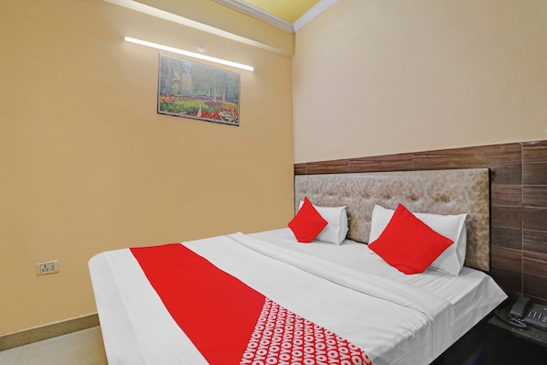 A hotel room with a bed, a painting on the wall, and a telephone on the side table. - Hotel O Four Square (Lucknow)
