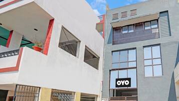 Un edificio de varios pisos con fachada plana, ventanas amplias y un letrero visible que dice 'OYO'.