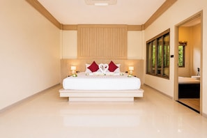 Habitación de hotel con una cama grande, dos lámparas de noche, cabecero de madera y vista a zonas verdes por una ventana.