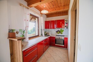 A kitchen with red cabinets, a wooden countertop, and a window with a view.