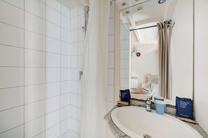 Ein Badezimmer mit Dusche, Waschbecken und Spiegel.