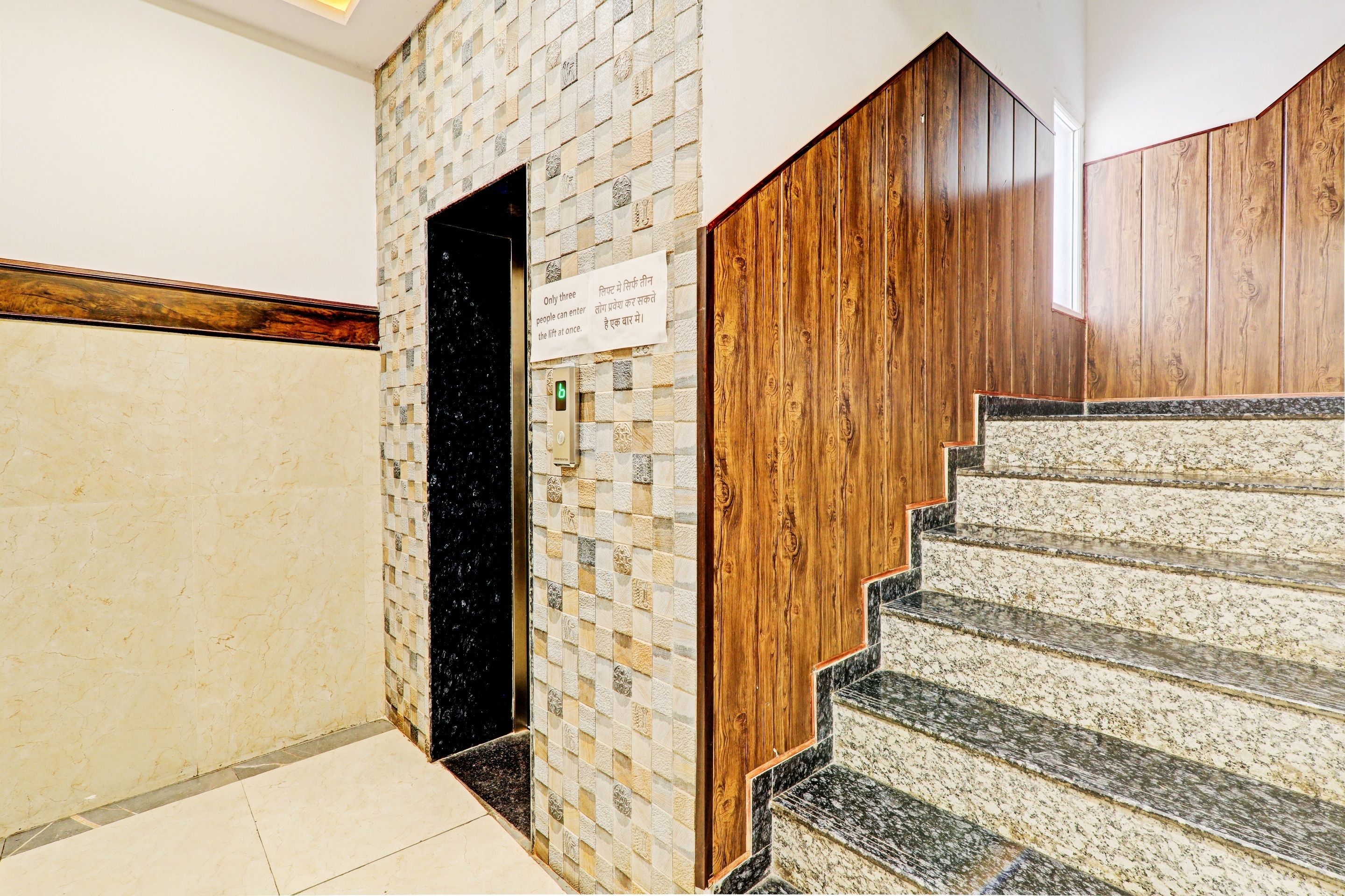 Una escalera con barandilla de madera y una pared con diseño de cuadros.