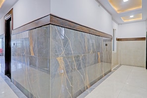 A lobby with a marble reception desk, a door, and a tiled floor. - Townhouse Jayati Oasis Inn (Lucknow)