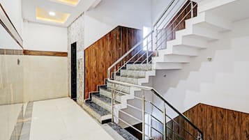 Una escalera moderna con detalles de madera y barandales de metal, que conduce a un rellano con piso de baldosas.
