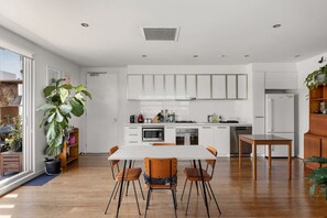 A modern kitchen with white cabinets, a central island, and a dining area with a table and chairs. - Parking included - unrivalled views of Kensington (Kensington)