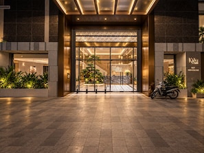 Entrada de hotel con diseño moderno, una recepción y una escalera que conduce a los pisos superiores.