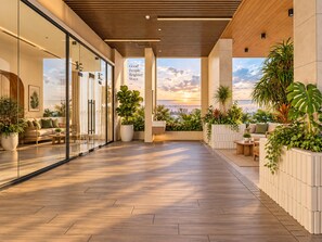 Un interior moderno con techo de madera, paredes de vidrio y vista al atardecer.