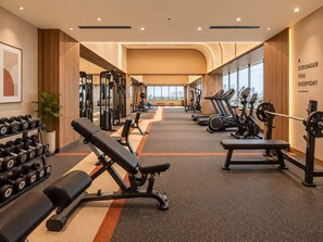 Un gimnasio con equipo de ejercicio variado, incluyendo cintas de correr, máquinas de pesas y mancuernas.
