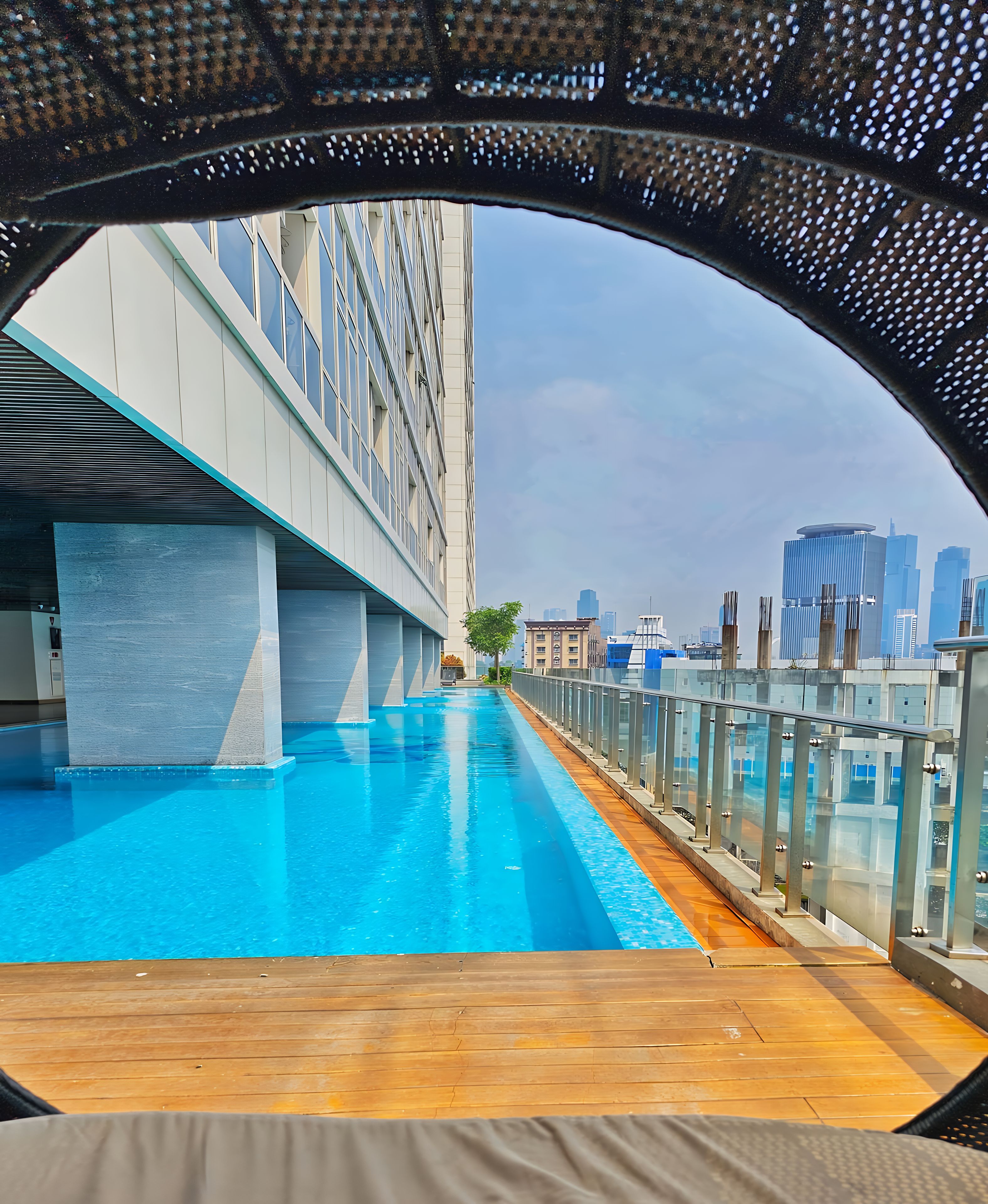 A modern urban pool with a clear view of a city skyline and a bridge in the background.