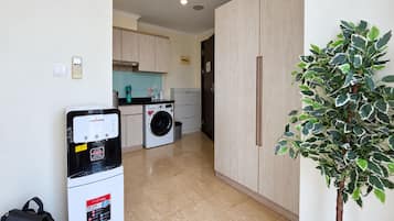 Una cocina compacta con lavadora, un refrigerador pequeño y una planta en maceta.