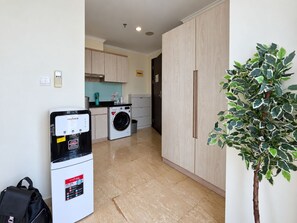 Una cocina compacta con lavadora, un refrigerador pequeño y una planta en maceta.