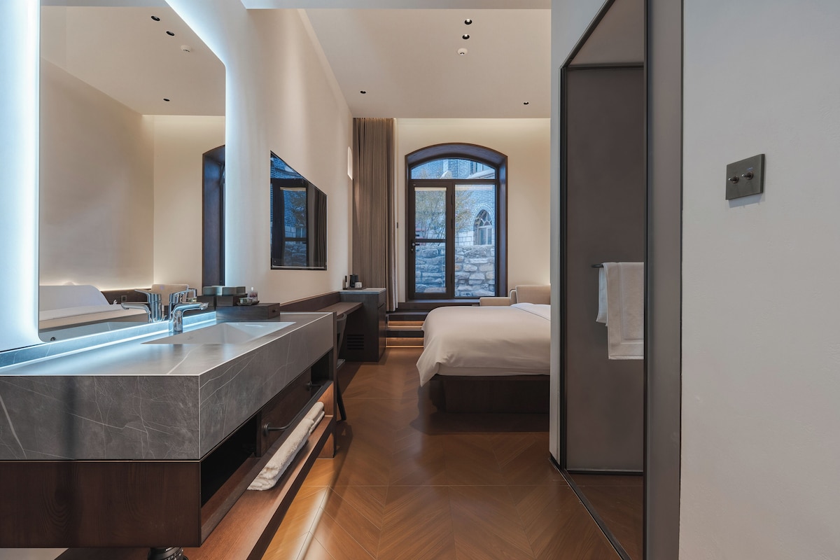 A modern bathroom with a large mirror, a double sink vanity, and a shower area.