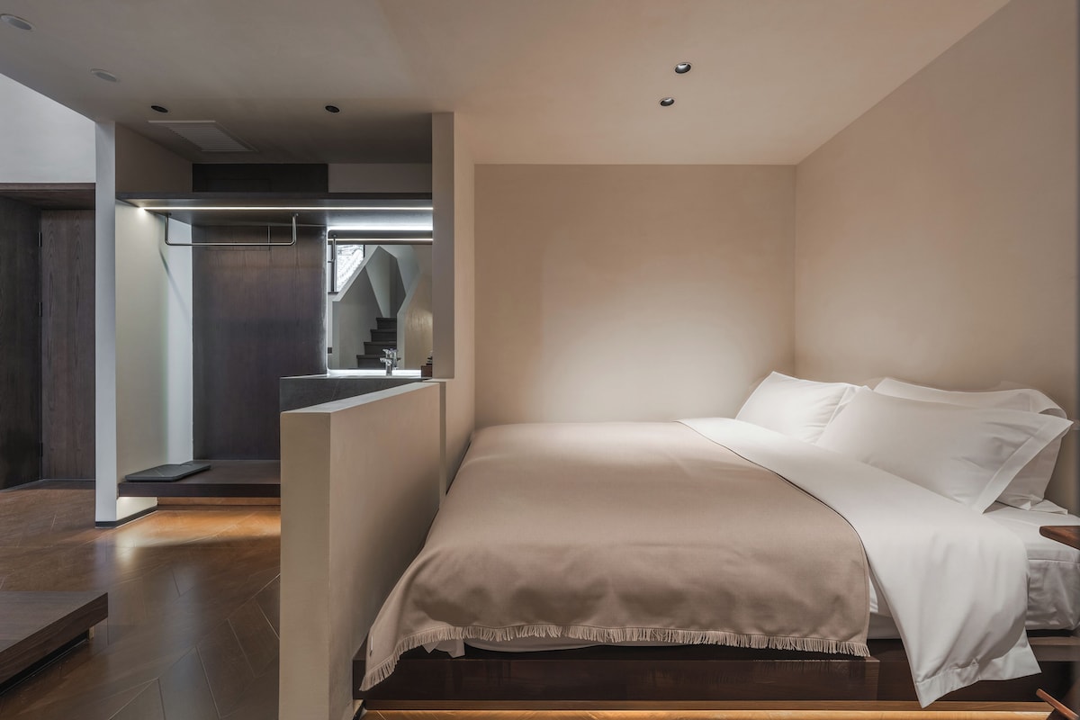 A modern bedroom with a bed, a nightstand, and a built-in bench.