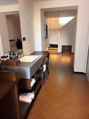 A modern bathroom with a large sink, mirror, and wooden vanity. There is a staircase leading to a bedroom with a bed and a window. - 17435924 (Jinan)