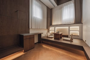 A modern interior with a wooden desk, a chair, and a small table with a lamp. - 17435924 (Jinan)