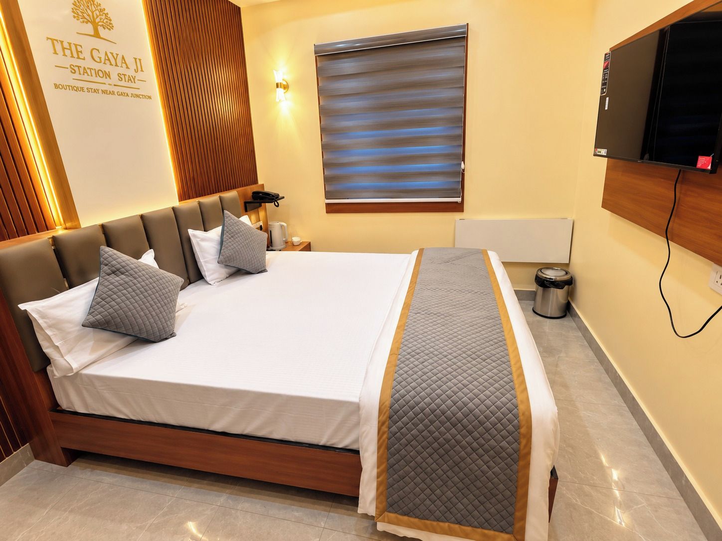 Habitación de hotel con una cama grande, televisión, mesita de noche y televisión montada en la pared.