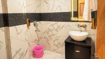 A bathroom with a white toilet, a sink with a black countertop, a mirror with a gold frame, and a shower area.