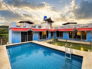 A hotel with a swimming pool, multiple guest rooms, and a view of the surrounding landscape. - Adiva Villa By Vintara Stays (Murud)