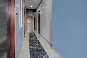 Un pasillo con suelo de mármol, paredes azules y un marco de puerta de madera.