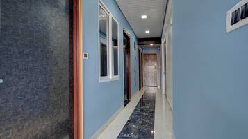 Un pasillo con paredes azules, piso de mármol y puertas que dan a habitaciones.