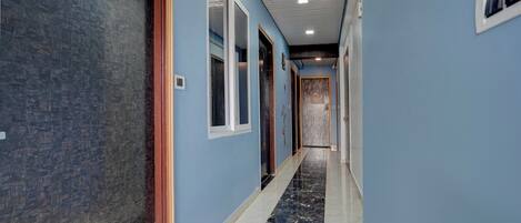 Un pasillo con paredes azules, piso de mármol y puertas que dan a habitaciones.