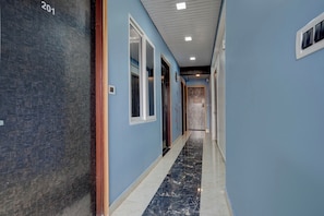 Un pasillo con paredes azules, piso de mármol y puertas que dan a habitaciones.
