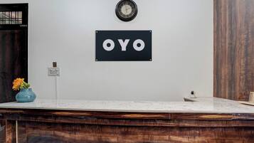 Una mesa de recepción con un reloj encima y un cartel que dice 'OYO'.