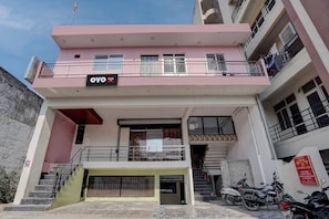 A multi-story building with a sign for 'OYO Swastik In' indicating a hotel or accommodation. There are balconies on the upper floors, a gated entrance, and a staircase leading to the entrance. - Hotel O Swastik Inn (Lucknow)
